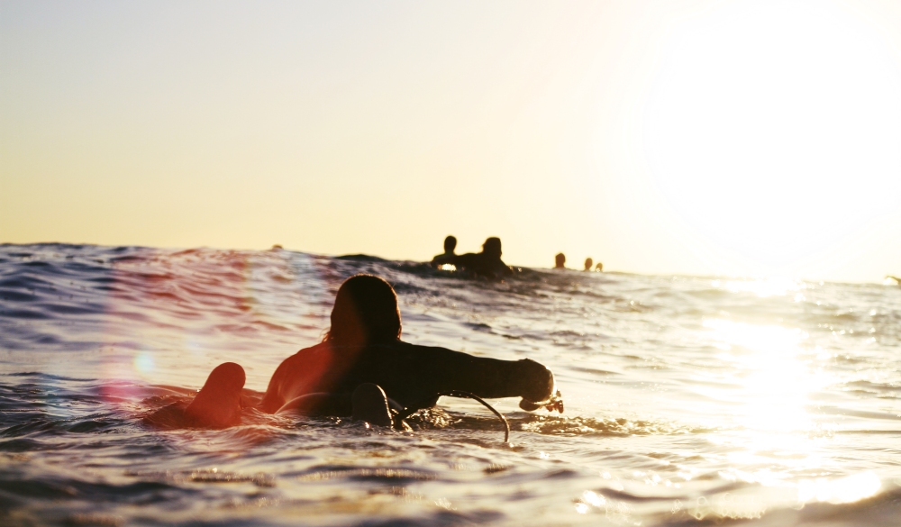 Man on surfer paddle at sunset.