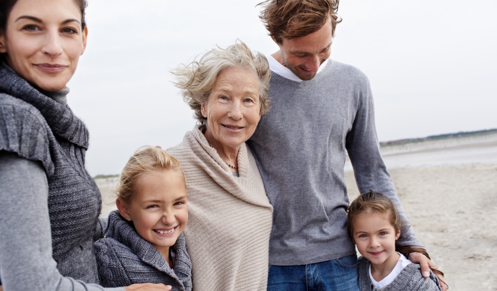 Happy family with grandmother on the beach, mother's day getaway