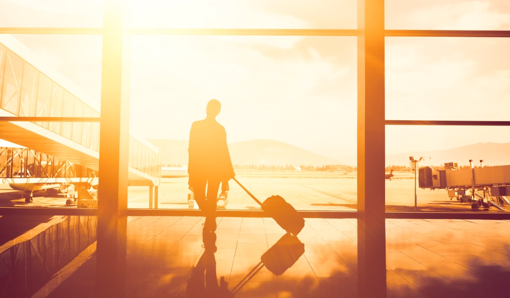 silhouette of young woman carrying her luggage in airport.back lit, photo taken at sunrise.
