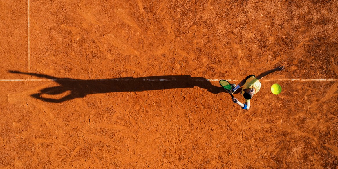 Tennis player on service. Mature adult man playing on court at sunny day.