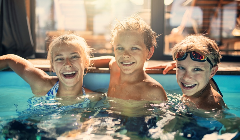 Kids enjoying swimming at indoors swimming pool. Kids are laughing at the camera.
Portrait shot with Nikon D850.