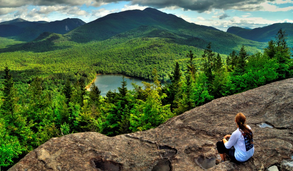 Female hiker takes in the view of the Adirondack High Peaks and Hear Lake from the summit of Mt. Jo.