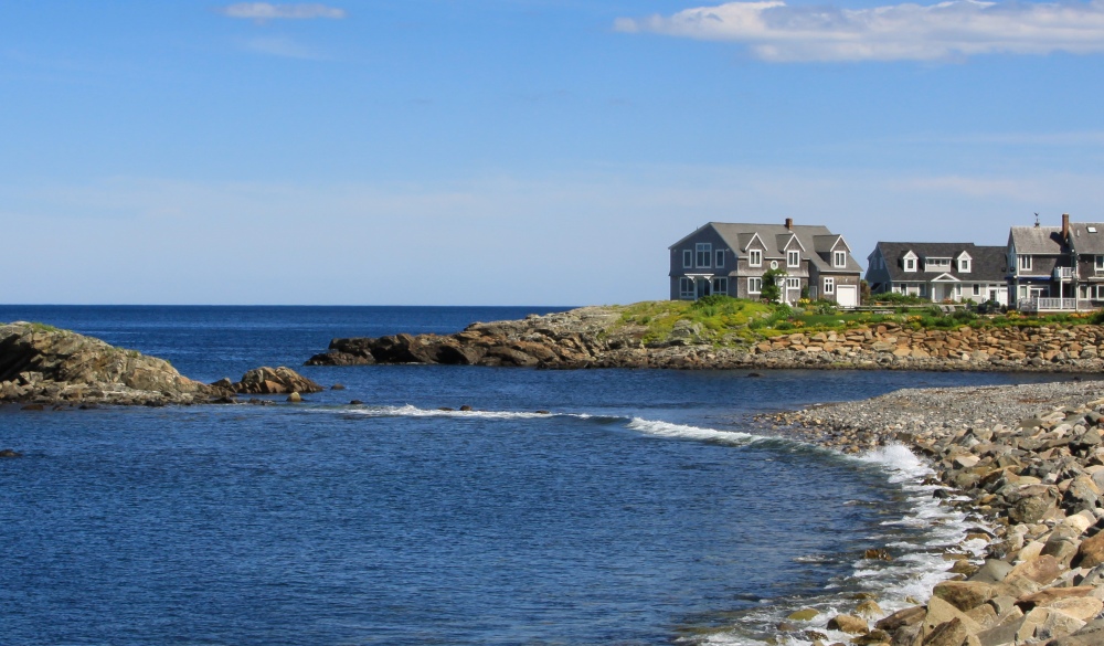 Harbor View with Rocks and Waterfront Houses, Perkins Cove, Ogunquit, Maine, USA. Deep blue ocean waters, rocky shore, green trees, bushes and vivid blue sky with clouds are in the image. Canon EF 24-105mm f/4 L IS lens. Polarizing filter.