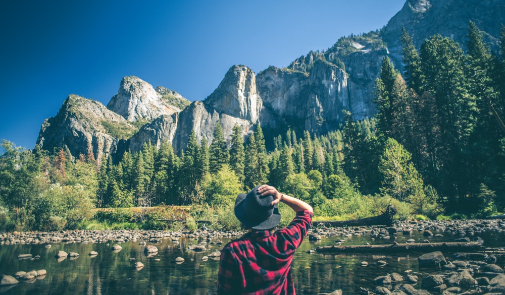 A shot of a young woman walking along a river in a majestic landscape.