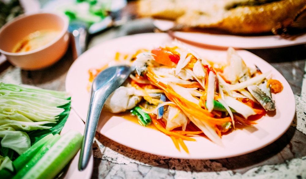 Som Tam - a famous Thai papaya / mango salad served on a plate in a local restaurant in Bangkok, Thailand.