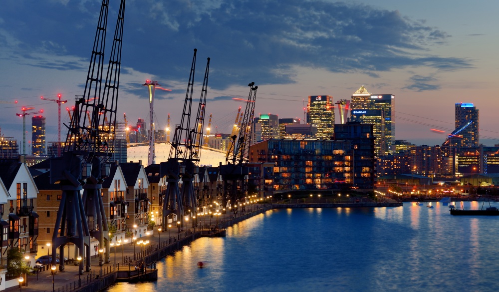 Elevated view of East London cityscape seen over Royal Victoria Dock at dusk. Including skyscrapers of Canary Wharf financial district, The O2 arena, London Cable Car and residential development