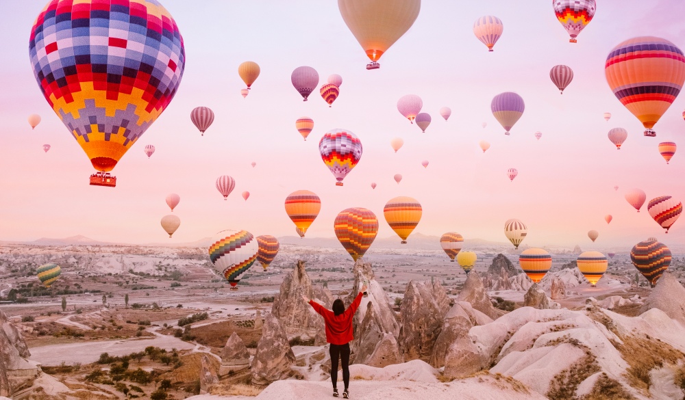 Young woman on a background of flying balloons at sunrise in Cappadocia