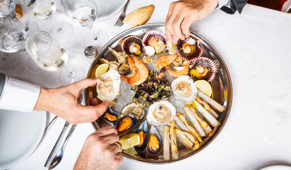 View from above of seafood plate and male hands picking food