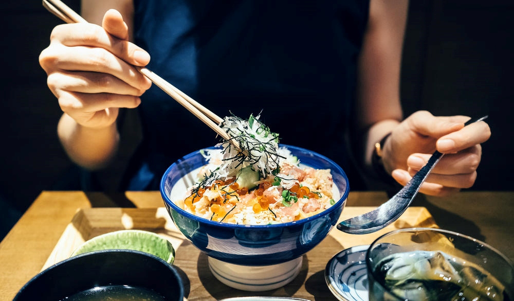 woman enjoying freshly served traditional Japanese seafood donburi 