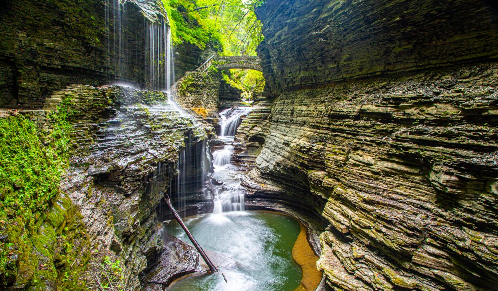 Natural rock formed by running water in gorge.  View of waterfall, natural pools and bridge at Watkins Glen State Park, New York, USA