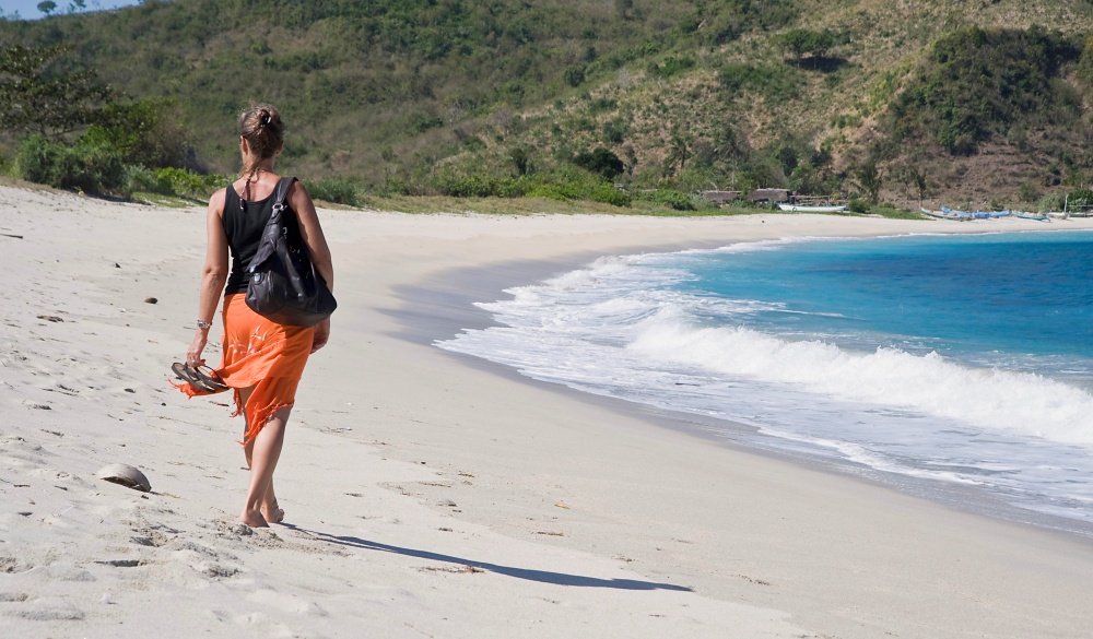 Woman walking along a deserted sandy beach, Kuta, Lombok, Indonesia, Southeast Asia