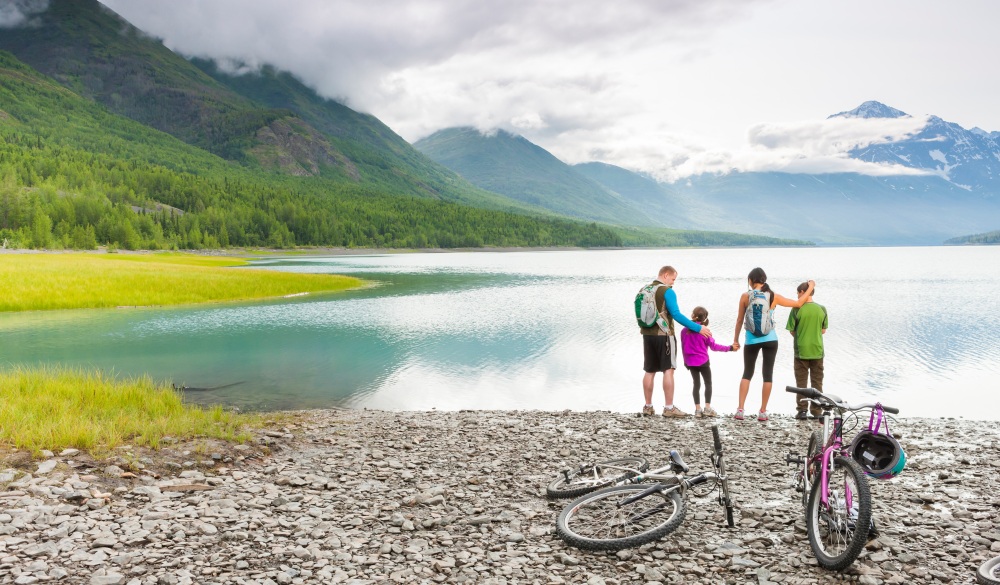 Couple with son and daughter riding bicycles near lake, destination to avoid crowds