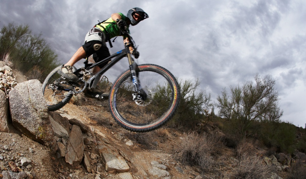 Man mountain biking down steep rocky path