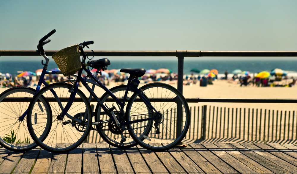 Bicycles in silhouette, propped by the edge of the boardwalk,