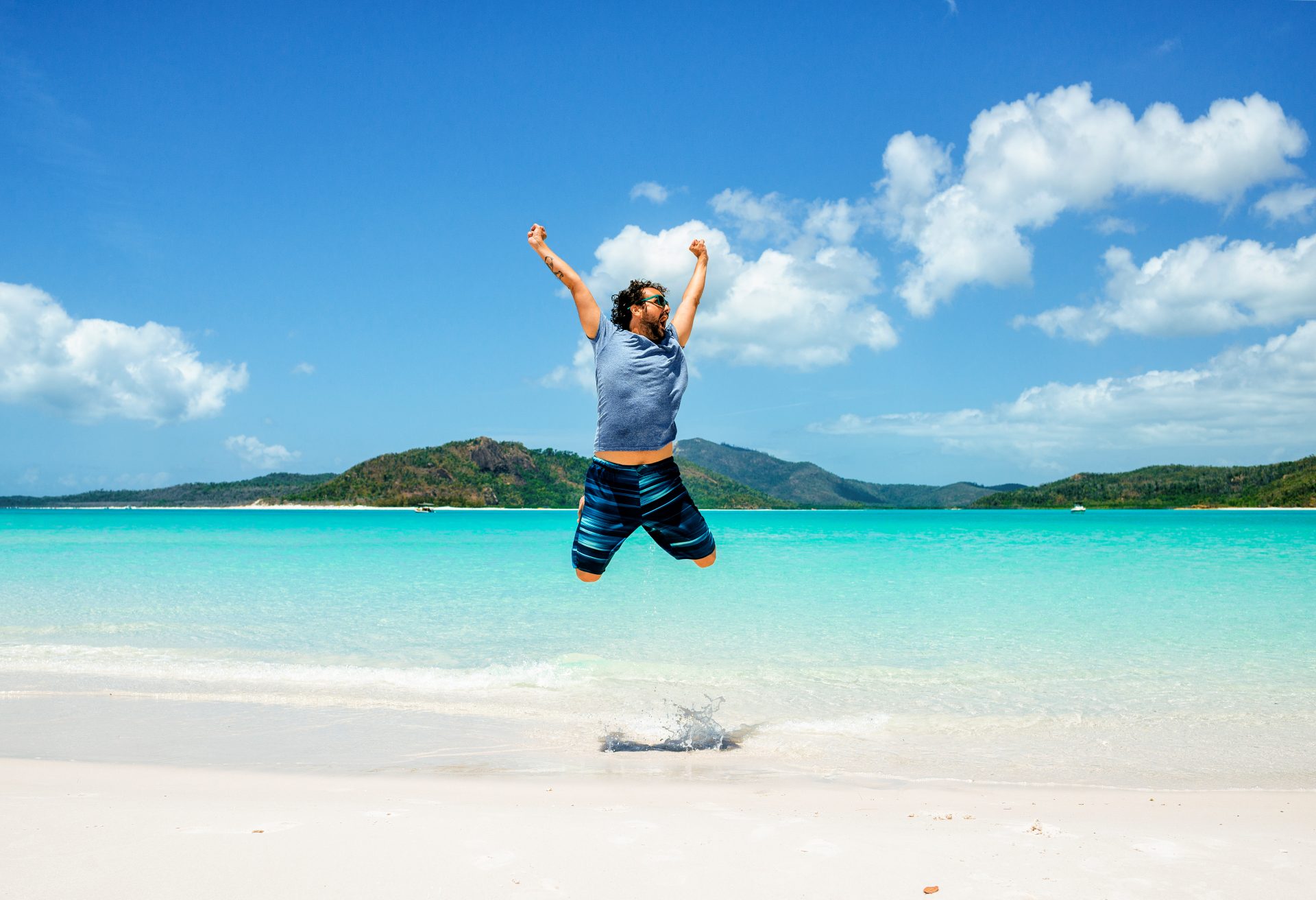 Australia, Queensland, Whitsunday Island, carefree man jumping at Whitehaven Beach