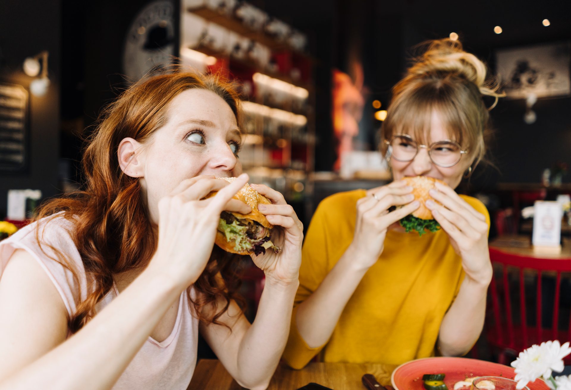 Two female friends eating burger in a restaurant