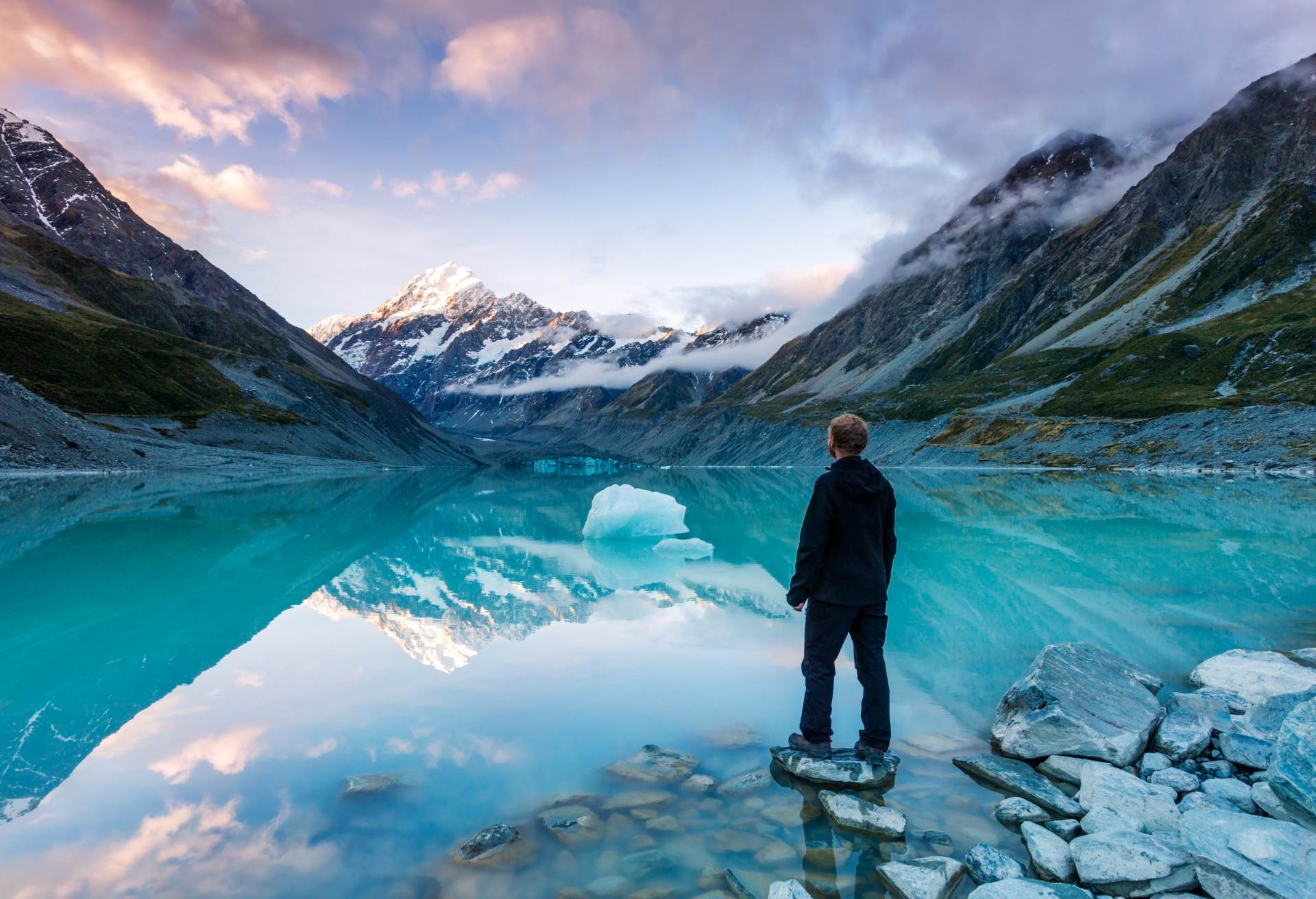 hiker looking at Mt Cook from lake with iceberg, New Zealand