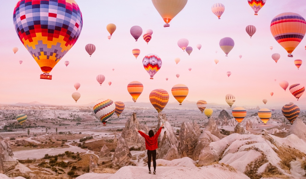 Woman watching flying balloons at sunrise in Cappadocia, ultimate travel bucket list