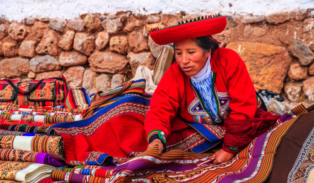 Peruvian woman selling souvenirs at Inca ruins.