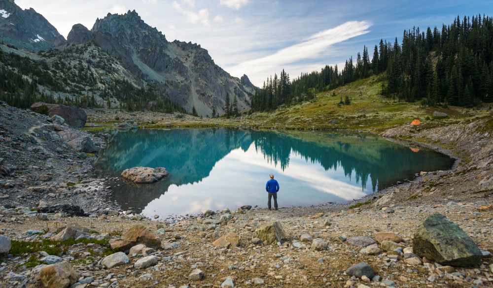 High angle view of hiker standing by lake against mountains at Olympic National Park, UNESCo site in the US