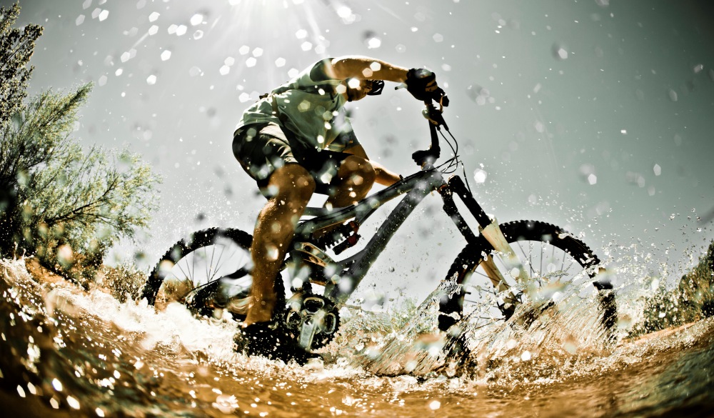 Man riding mountain bike through water, bike trails