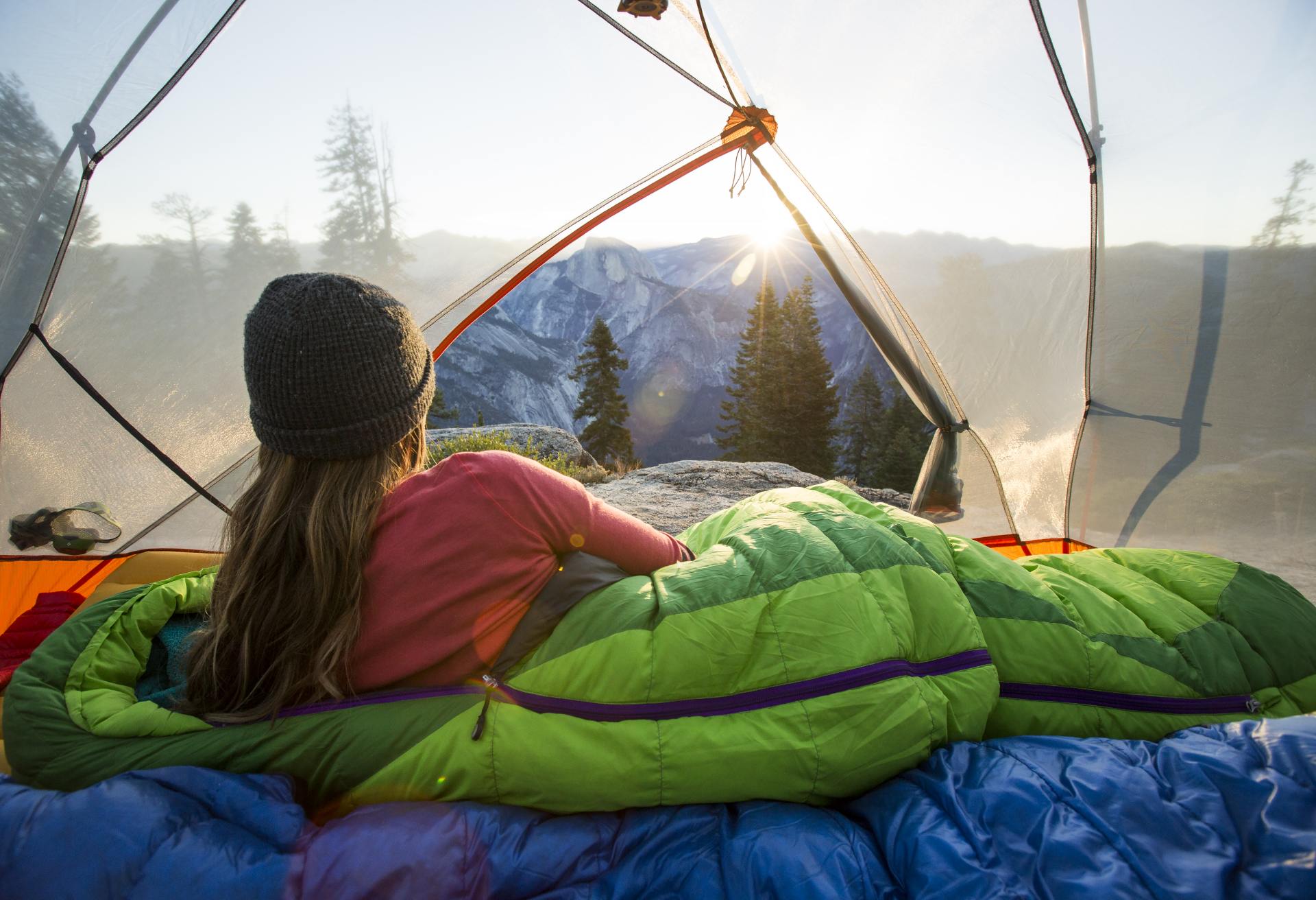 A woman watching sunrise from a tent.