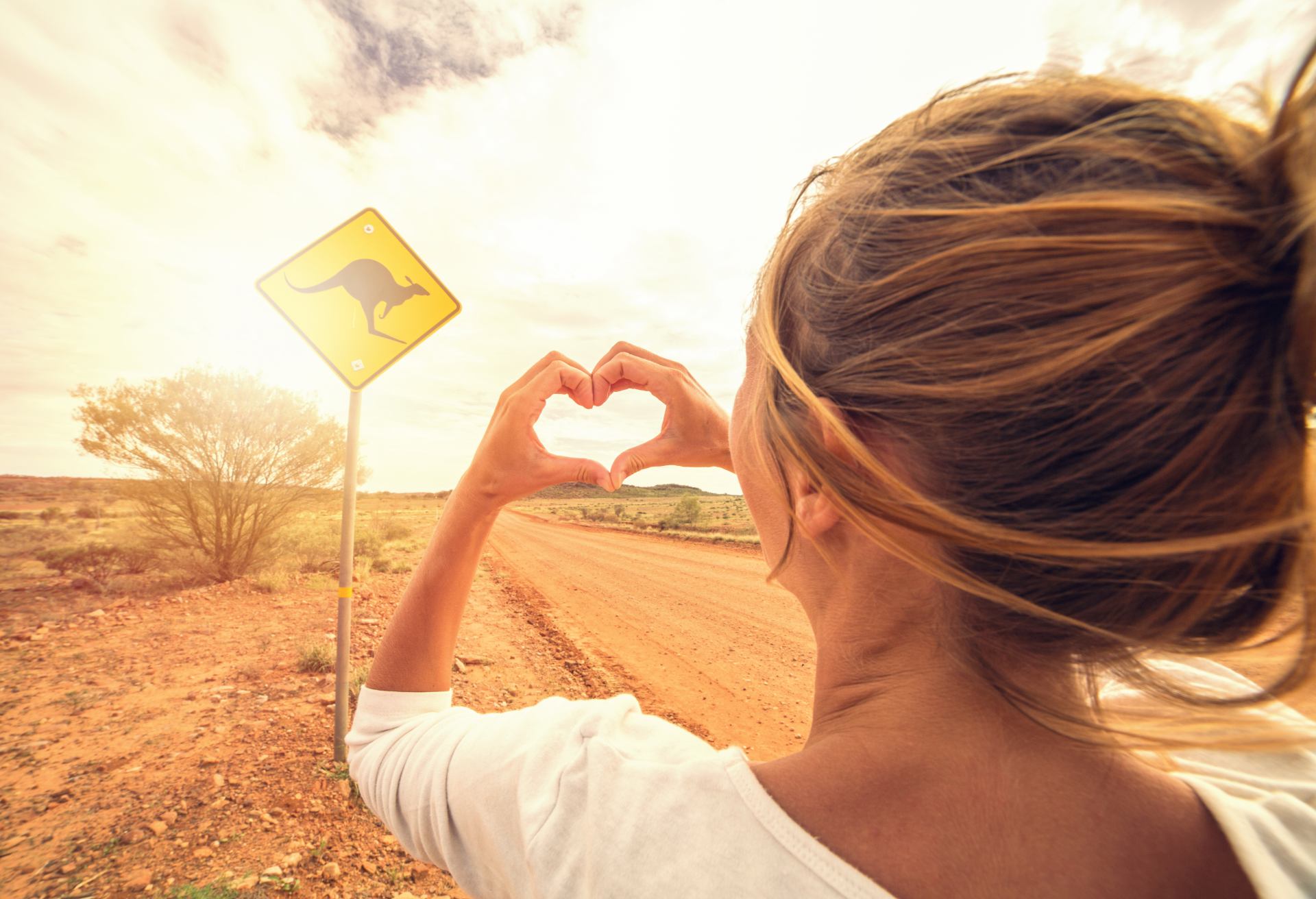 Young woman on the road standing next to a kangaroo warning