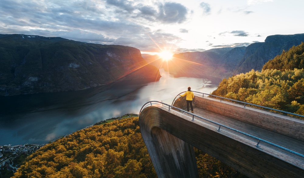 Tourist admiring the sunset over norwegian fjord, Norway, best lake getaways