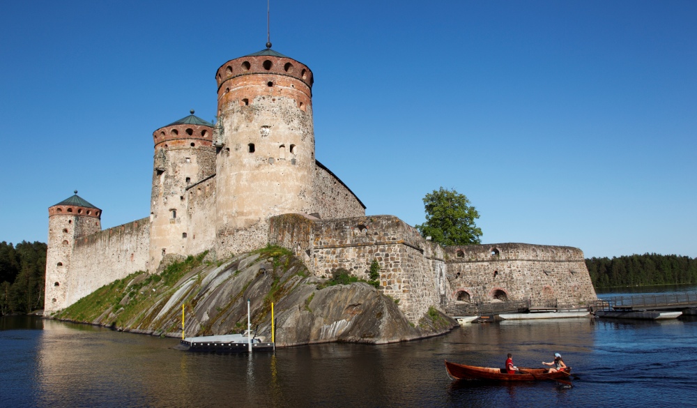 Boat passing Olavinlinna Castle on Lake Saimaa, best lake getaways