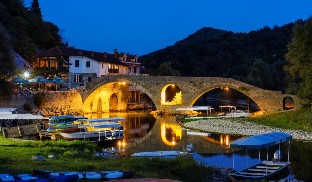 Excursion boats and Old Bridge Stari most at dusk, river Crnojevic, Rijeka Crnojevica, national park Lake Skadar, province Cetinje, Montenegro