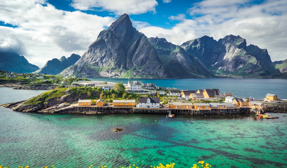 yellow wooden traditional houses on the sea near mountain range in background, Lofoten Islands, Norway