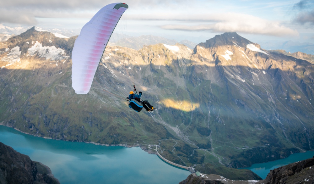 Man paragliding above alpine water reservoirs above Kaprun, Zell am See, Salzburg, Austria