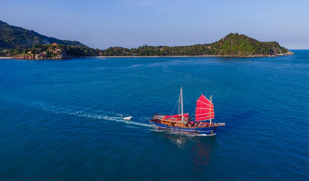  red sailing ship is coming by the sea