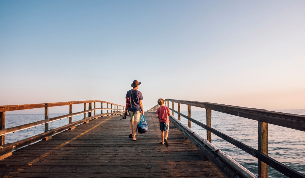 Rear view of father and son walking on pier, Goleta, California, United States, North America