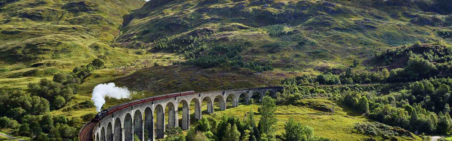 UK, Scotland, Highlands, Glenfinnan viaduct with a steam train passing over it