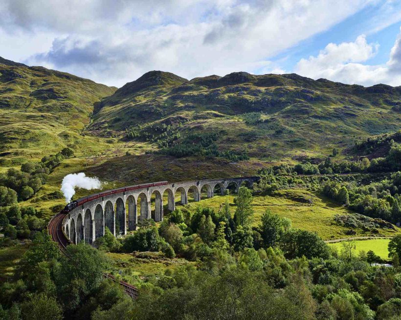 UK, Scotland, Highlands, Glenfinnan viaduct with a steam train passing over it