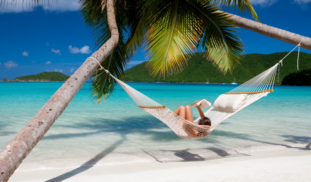 woman reading a book in hammock at the Caribbean beach