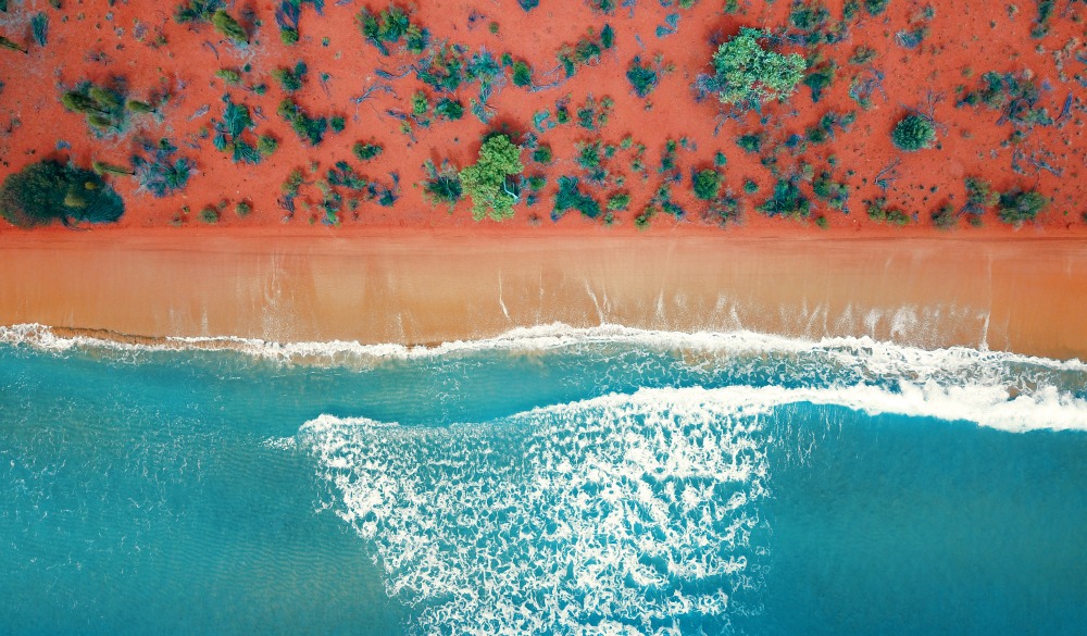 Aerial top view of a bright orange sandy beach