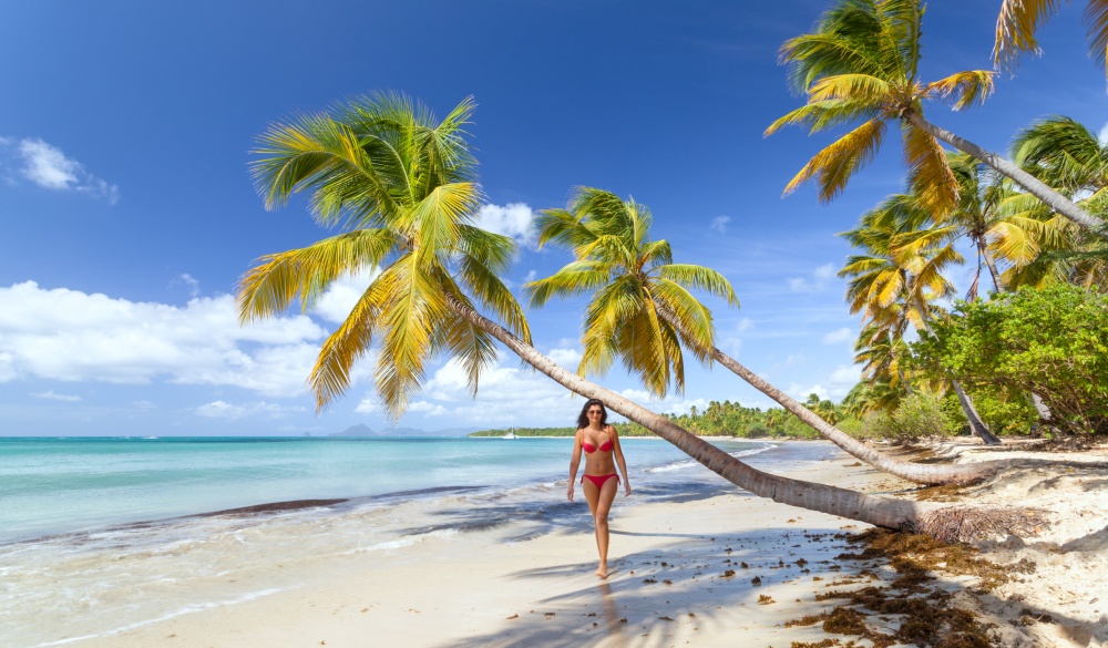 Woman in red bikini walking on tropical beach in the Caribbean