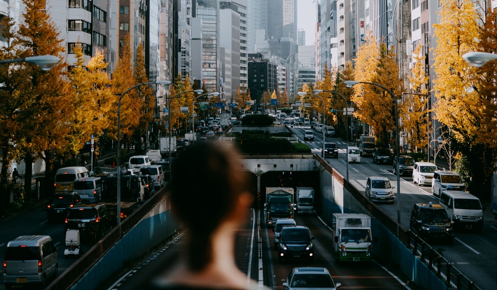 Woman looking at Tokyo city street with yellow ginkgo trees