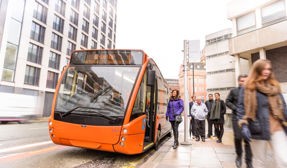 Passengers at bus stop waiting to board electric bus