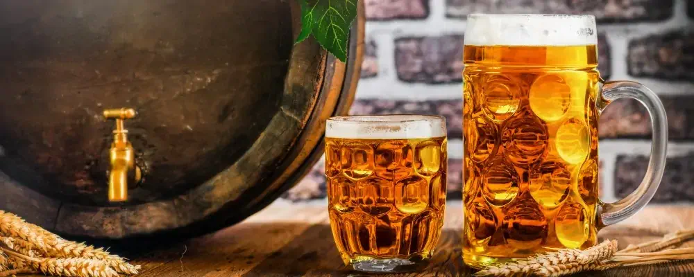 Beer glasses and beer barrel with wheat on wooden table in a cellar. Gold pint beers.; Shutterstock ID 1486043570