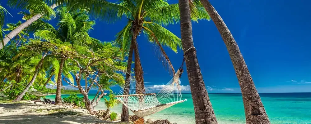 Empty hammock in the shade of palm trees on vibrant tropical Fiji Islands