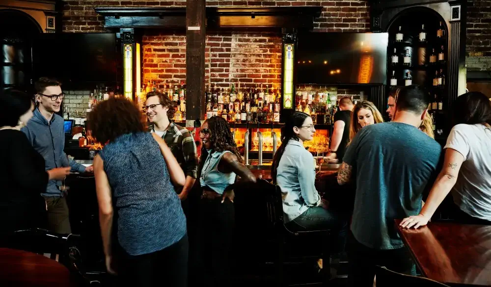 Group of friends sharing drinks in busy bar