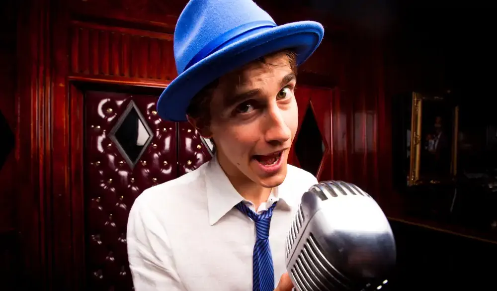 A lounge singer or comedian with a retro microphone on stage at a seedy dive bar adorned in red leather and wood paneling