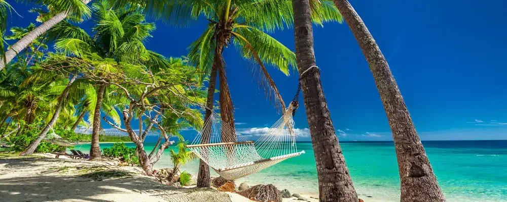 Empty hammock in the shade of palm trees on vibrant tropical Fiji Islands