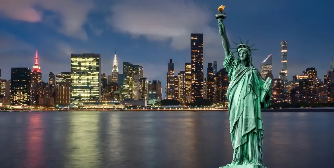 Statue of liberty in front of Manhattan skyline, at night, during blue hour