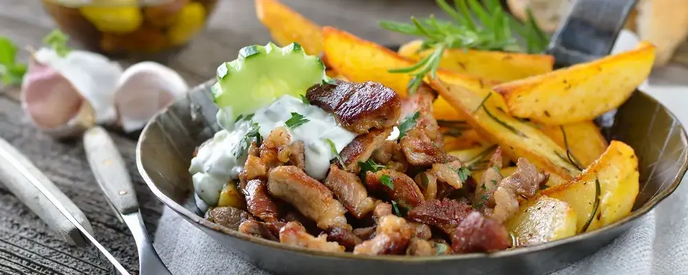Greek pork gyros with tzatziki and fried potatoes, served with pitabread, salad and olives