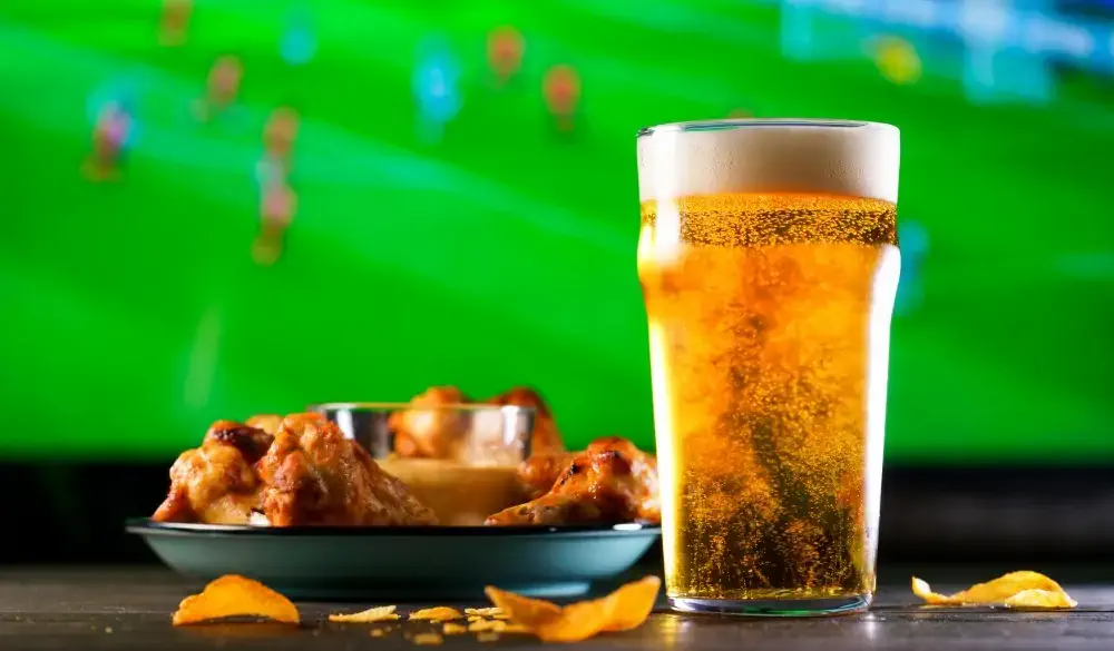 A glass of beer and hot chicken wings