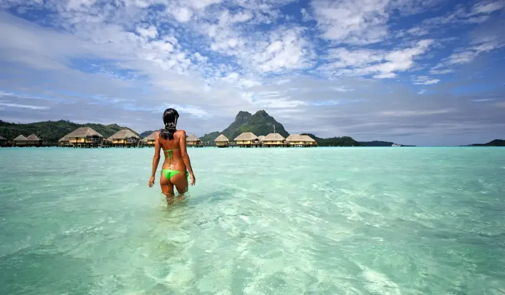 Woman in lagoon waters of bora bora relaxing and carefree in bora bora, Tahiti, French Polynesia.